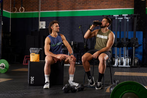 2 males in gym sitting down drinking Pro Matrix from shaker bottle