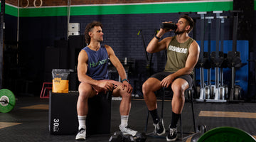 2 males in gym sitting down drinking Pro Matrix from shaker bottle