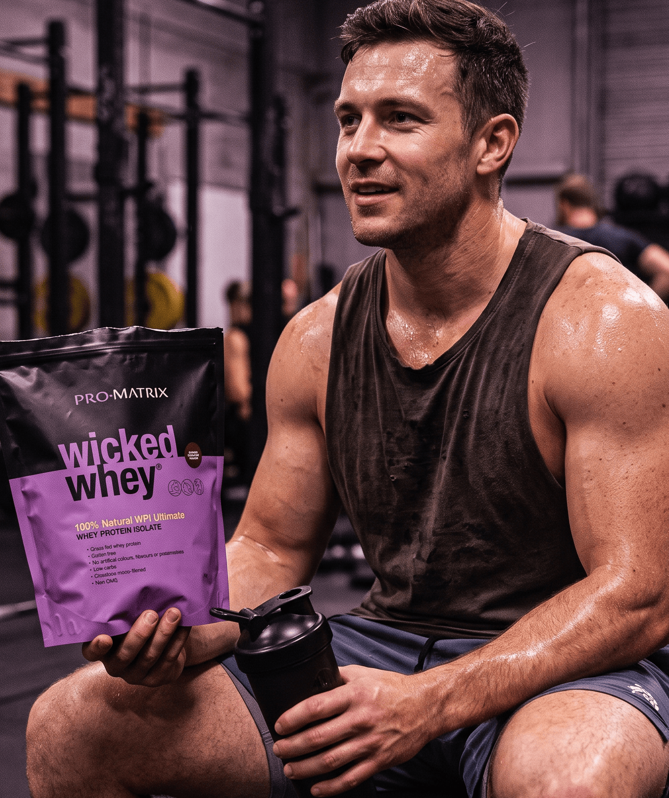Man sitting on gym floor with Wild Whey protein powder and supplements
