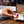Load image into Gallery viewer, PROLLIES PROTEIN SNACKS PROLLIES - Whey protein lollies (BOX OF 10) Neapolitan Flavour. Person at desk with computer in background picking up prollies with open packet on bench. Pink prollie in shape of dumbbell
