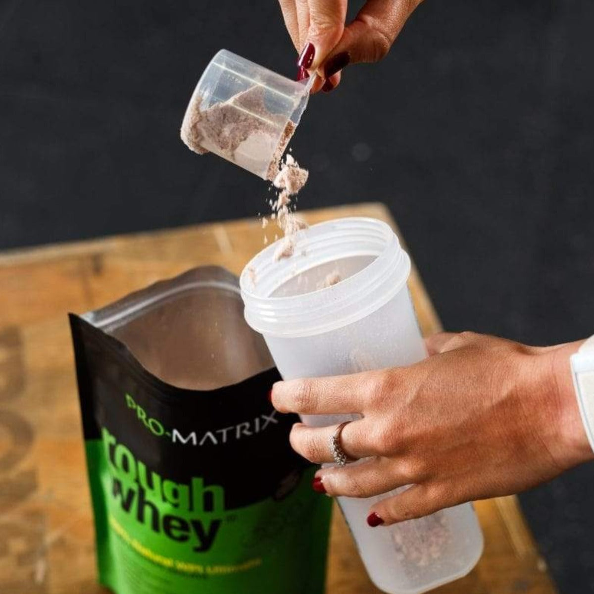 ROUGH WHEY WHEY PROTEIN POWDERS 1kg CHOCOLATE &amp; COCONUT, Isolate ROUGH WHEY Girls hand pouring protein powder from scoop in to shaker with rough whey on table in background