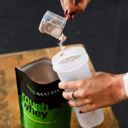 ROUGH WHEY WHEY PROTEIN POWDERS 1kg CHOCOLATE &amp; COCONUT, Isolate ROUGH WHEY Girls hand pouring protein powder from scoop in to shaker with rough whey on table in background