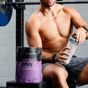 WICKED WHEY WHEY PROTEIN POWDERS 1kg CHOCOLATE, Isolate WICKED WHEY. man at gym with shirt off holding pro matrix shaker bottle. Pro Matrix wicked whey packet in foreground