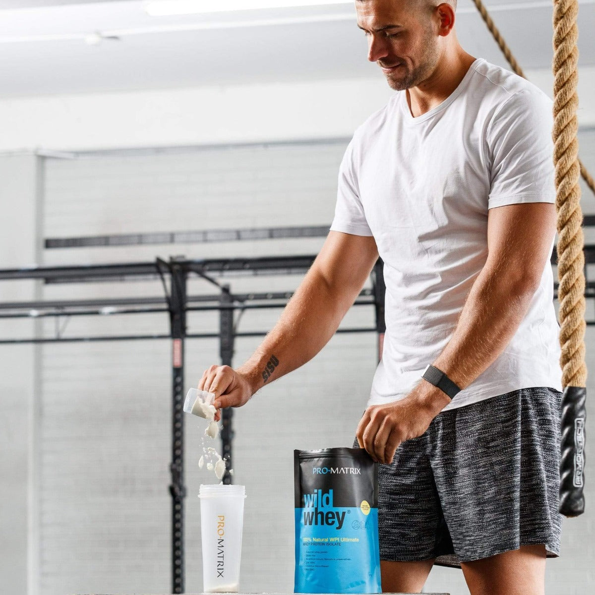 WILD WHEY WHEY PROTEIN POWDERS 2kg VANILLA, Isolate WILD WHEY. Man in gym scooping wild whey from packet in to pro matrix shaker